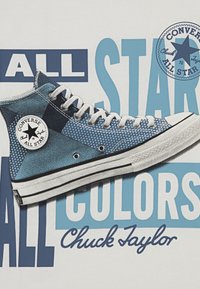 Høye Converse Chuck Taylor-sneakers i forskjellige nyanser av blått, med et teksturert stoff og en hvit gummisåle med en svart stripe.