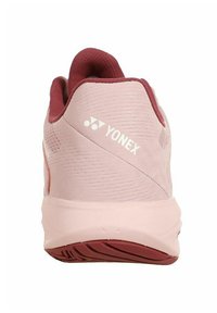 Scarpa sportiva Yonex di un rosa chiaro con una tomaia testurizzata, dettagli in bordeaux e una suola robusta con un battistrada lavorato per una buona aderenza.