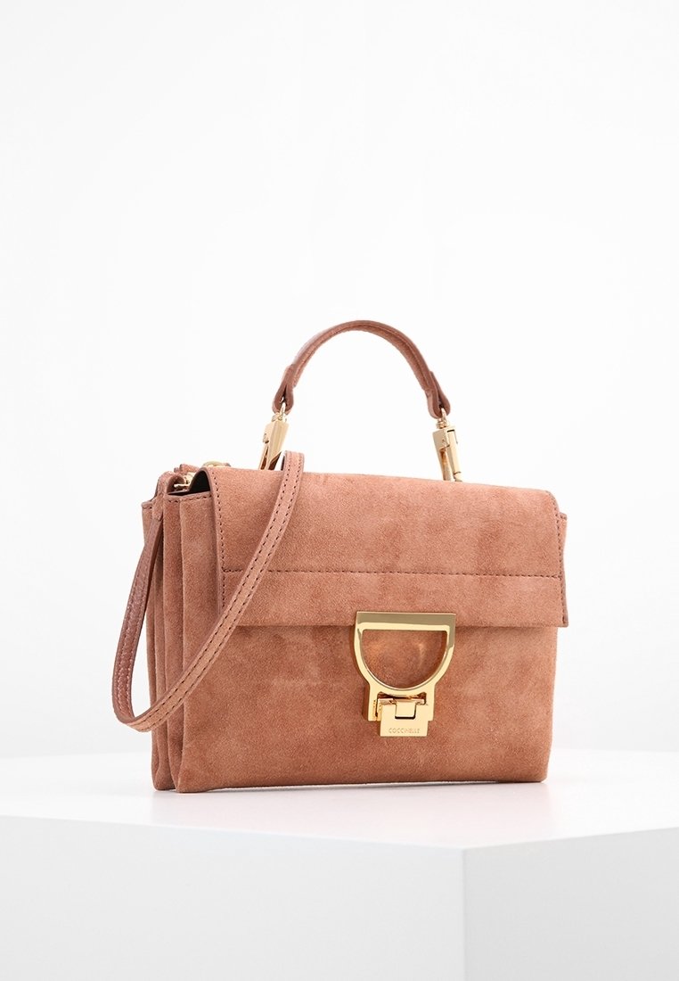 Kleine rosa Wildleder-Handtasche mit strukturiertem Design, goldenen Beschlägen, abnehmbarem Tragegurt und einem Frontverschluss. Texturierte Oberfläche mit sauberer Näharbeit.