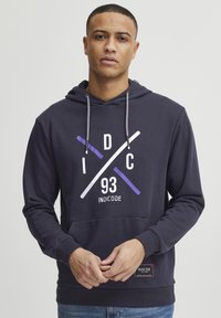 Granatowy hoodie z kieszenią z przodu, szarymi sznurkami i abstrakcyjną grafiką w purpurowym i białym kolorze, na której znajduje się napis "93" oraz logo "INDICODE".