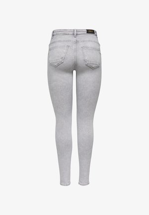 Sivé priliehavé džínsy z denimu. Majú vysoký pás, päť vreciek a hladkú textúru so slabým vyblednutím. Na zadnom páse je viditeľná nálepka.