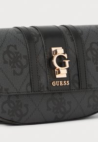 Black textured handbag with a monogram pattern. Features a central gold logo emblem and black leather accents. Rectangular shape.