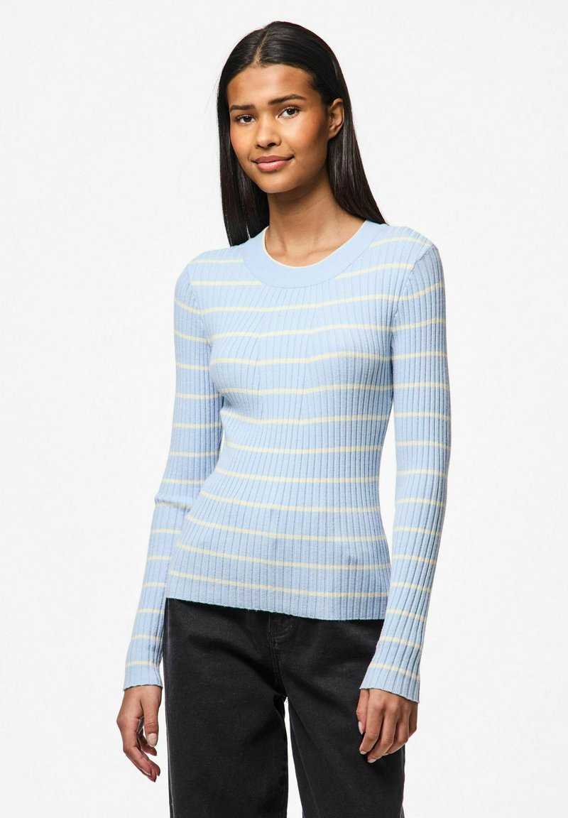 Ljust blå ribbad tröja med gula ränder, långa ärmar och rund halsringning, i kombination med mörka jeans. Texturen är mjuk och åtsittande.