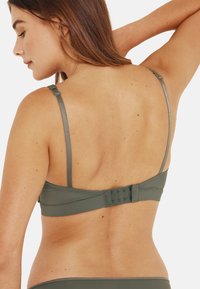 Bralette vert olive avec des bretelles réglables, une texture lisse et une fermeture à crochets à l'arrière pour un ajustement sécurisé.