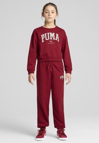 Bordová športová mikina PUMA a zodpovedajúce tepláky; má odvážny biely logo, rebrované manžety a elastický pás pre nastaviteľné nosenie.