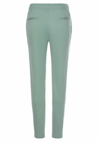 Svetlozelené, priliehavé nohavice s elastickým pásom, dvoma zadnými vreckami a hladkým povrchom, navrhnuté pre voľný čas.