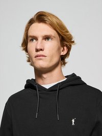 Svart hoodie med dragsko, med en liten vit golfare-logotyp på bröstet. Mjuk material och avslappnad passform.