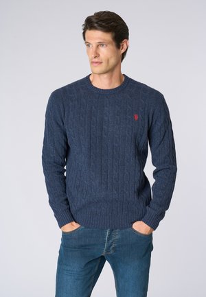 Maglione blu navy a maglia con scollo rotondo e polsini a costine. Presenta un piccolo logo rosso sul lato sinistro del petto. Abbinarlo a jeans blu.