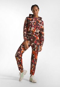 Set di felpa e pantaloni jogger con un vivace motivo astratto che presenta colori rosso, arancione, marrone e crema; tessuto leggero, vestibilità comoda, design con cappuccio.