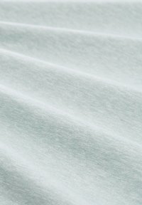 Tela de un verde menta claro con una textura suave, que presenta variaciones sutiles en el tono y pliegues suaves que crean profundidad y dimensión.