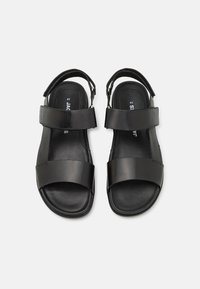 Black leather sandals featuring two wide straps across the foot and a back strap for support. Smooth texture and flat sole design.