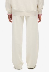 Lyse beige bukser med vide ben i blødt materiale, med en afslappet pasform, elastisk talje og enkelt design uden mønstre eller pynt.