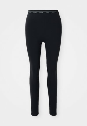 Zwarte legging gemaakt van rekbaar materiaal. Beschikt over een brede elastische tailleband met het "GUESS"-logo dat over de voorkant is gedrukt. Glad van textuur.