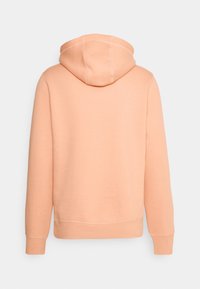 Sudadera con capucha de color melocotón, con una textura suave, capucha con cordón y puños acanalados. Presenta costuras en contraste. Vista trasera mostrada.