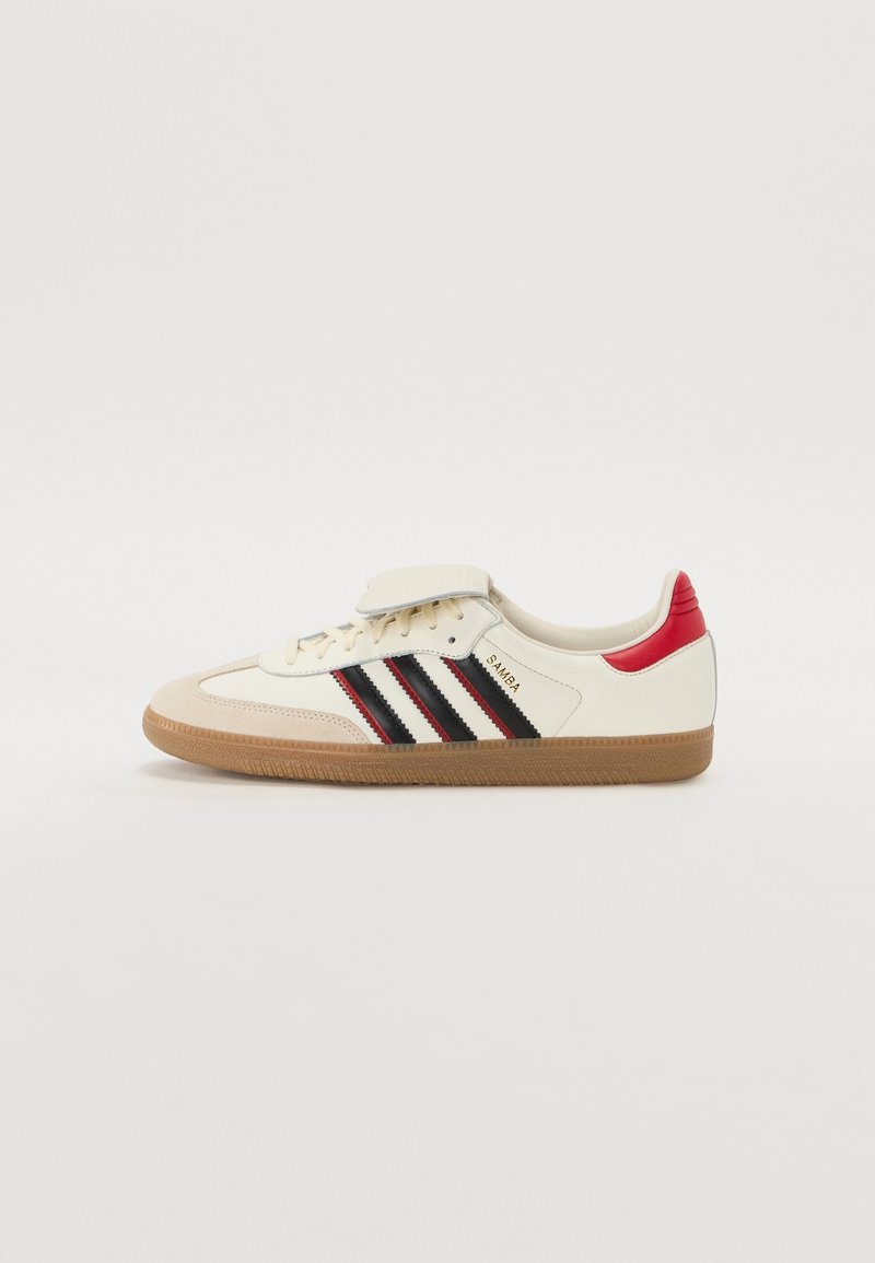 Krämfarbene Adidas Samba Sneaker mit schwarzen Streifen, roten Akzenten an der Ferse und Gummisohle, seitlich auf einem weißen Hintergrund dargestellt.