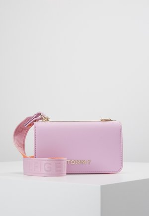 Roze tas van synthetisch leer met een goudkleurige ritssluiting, logo "TOMMY" en een afneembare, gestructureerde band in roze en oranje.