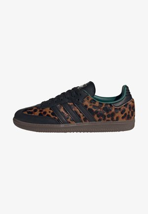 Sneaker in pelle nera con dettagli a stampa leopardata, caratterizzato da tre strisce scure, suola in gomma e un interno imbottito verde.