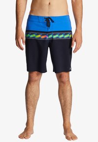 Niebiesko-czarne kąpielówki posiadają kolorowy wzór fal na wysokości pasa, płaski pas ze sznurkiem oraz gładką fakturę materiału.