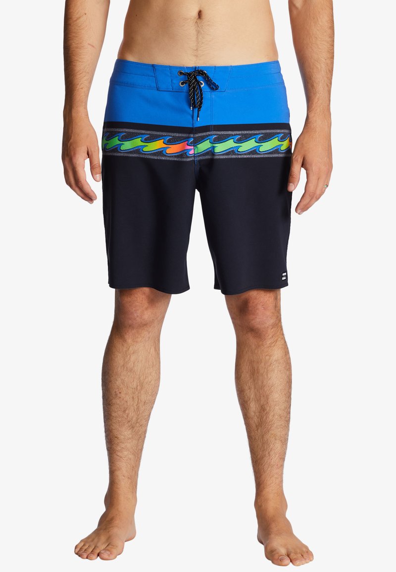 Niebiesko-czarne kąpielówki posiadają kolorowy wzór fal na wysokości pasa, płaski pas ze sznurkiem oraz gładką fakturę materiału.