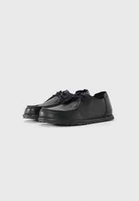 Black leather lace-up casual shoes with textured surface and flat rubber soles viewed at slight angle on white background.