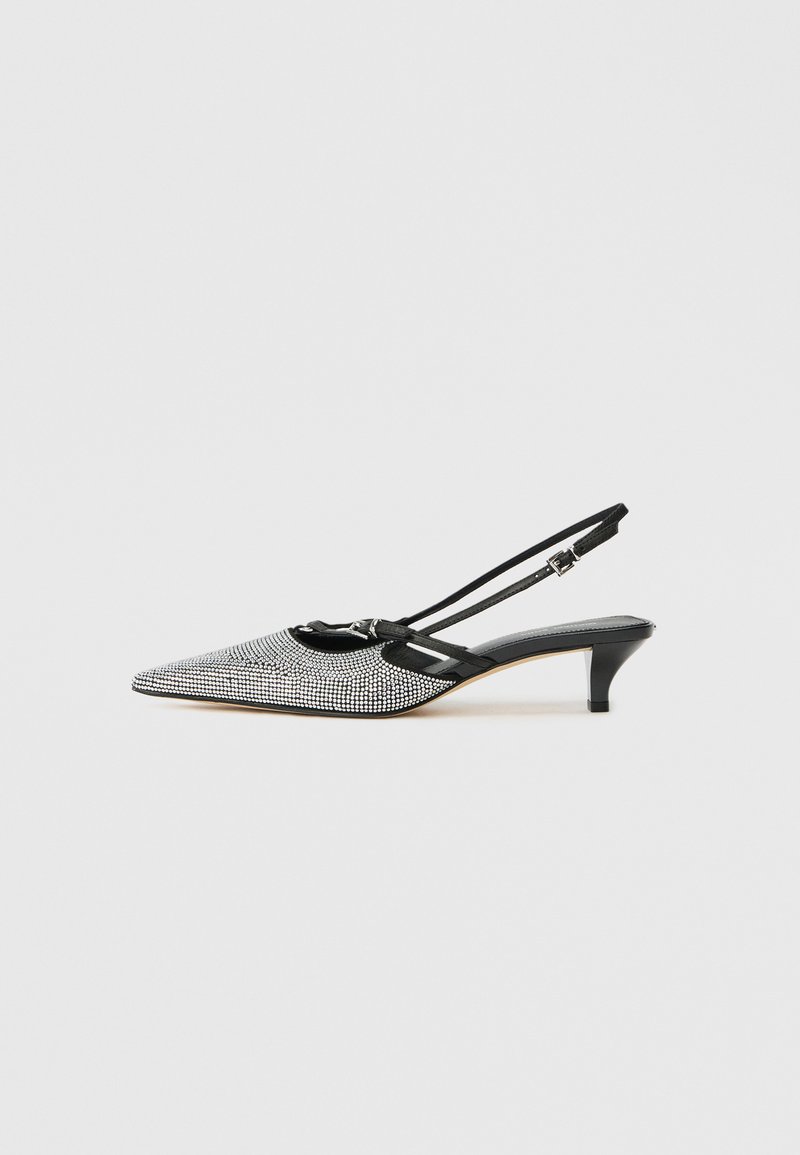 Slingback apavi ar norādītu purngalu, melnbalto kristālu rotājumiem un zemu kaķēnu papēdi. Regulējams siksniņa drošai piegulšanai.