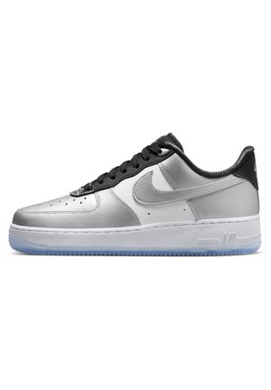 Nízké tenisky Nike Air Force 1 ve stříbrné a bílé barvě s černými tkaničkami a patním proužkem, s průhlednou modrou podrážkou.