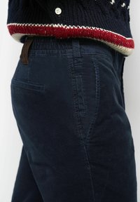 Navy corduroy pants with a textured finish, featuring a waistband, side pockets, and a leather patch at the back.