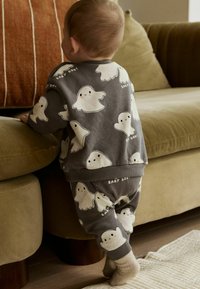 Tenue pour tout-petit grise avec un imprimé fantôme, dotée d'un col rond et de poignets élastiques, assortie d'un pantalon. Tissu doux, coupe confortable.