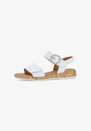 White sandal featuring a cork sole and a broad strap with a circular silver buckle accent. Smooth texture and open-back design.
