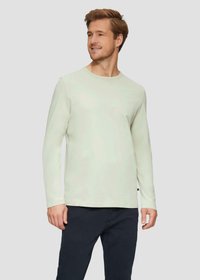 Helles grünes Langarm-T-Shirt mit rundem Ausschnitt, gefertigt aus glattem Stoff, kombiniert mit dunklen Hosen. Ordentlicher Schnitt mit minimalen Details.