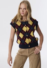 Ärmelloser Pullover aus Strick in einem marineblauen, gelben und burgunderfarbenen Rautenmuster, mit rundem Ausschnitt, zwei Knöpfen und einem gerippten Saum.