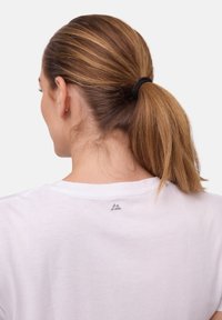 Biała bawełniana koszulka z okrągłym dekoltem i krótkimi rękawami, z małym szarym logo na górnej części pleców blisko dekoltu.