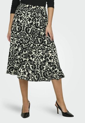Jupe midi à motifs noir et crème avec une taille ajustée et un ourlet fluide, accompagnée de chaussures à talons hauts noires. Tissu lisse et léger.