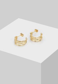 Zelta auskari ar trim slāņiem, kuros ir mazi caurspīdīgi dārgakmeņi, kas iestatīti gar ārējo malu. Elegants, minimālistisks dizains.