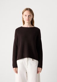 Maglione a coste marrone scuro con scollatura ampia e maniche lunghe, caratterizzato da una vestibilità rilassata e orlo dritto. Abbinato a pantaloni beige chiaro.