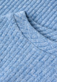 Hellblauer, gerippter Strickstoff mit weicher, flauschiger Textur und rundem Ausschnitt, zeigt eine detaillierte Nahaufnahme der Textilfasern.