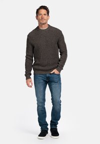 Donkergrijze gebreide trui met een ronde hals, textuurpatroon, gecombineerd met blauwe slim-fit jeans en zwarte schoenen, staand tegen een witte achtergrond.