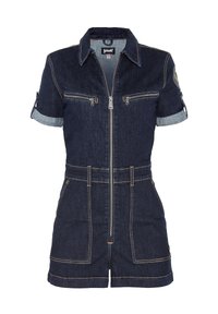 Tuta in denim con maniche corte, tessuto blu scuro, zip frontale, due tasche sul petto e polsini delle maniche arrotolati. Cuciture a contrasto in tutto il capo.