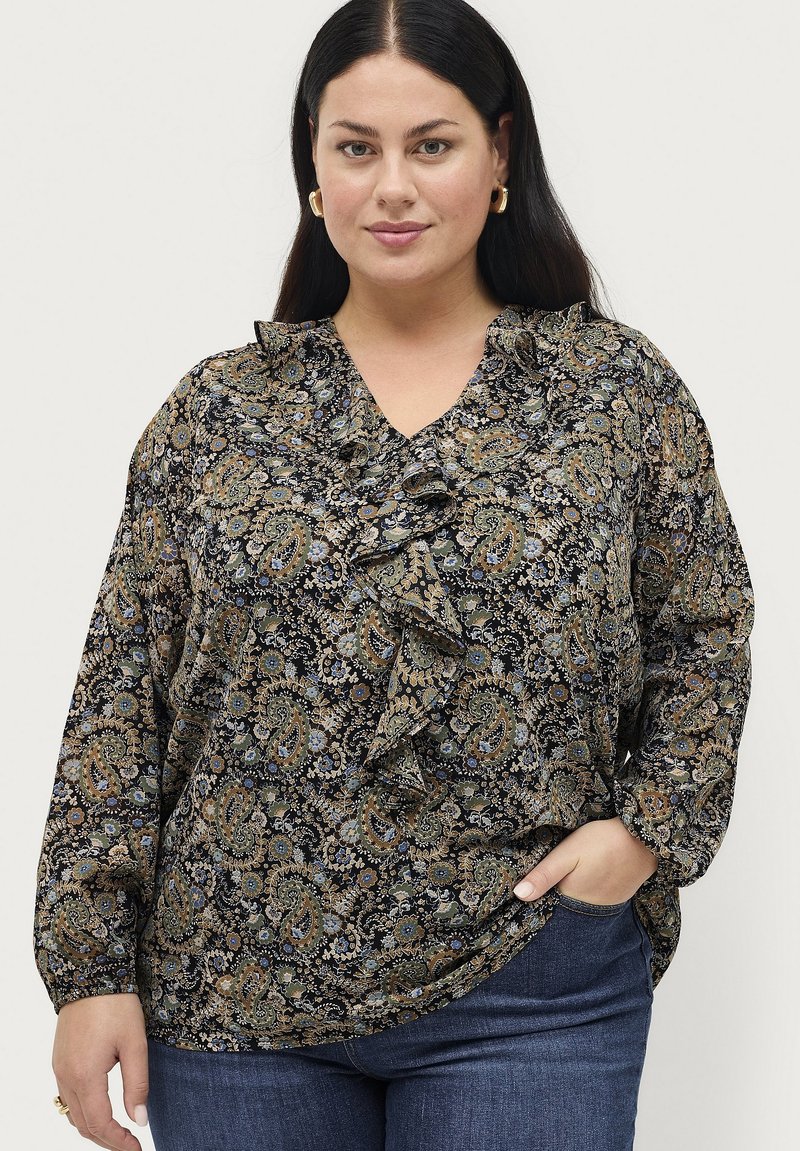 Zwarte blouse met een paisleypatroon in blauw, groen en beige. Heeft een gerimpelde halslijn en lange mouwen. Draagt bij jeans.