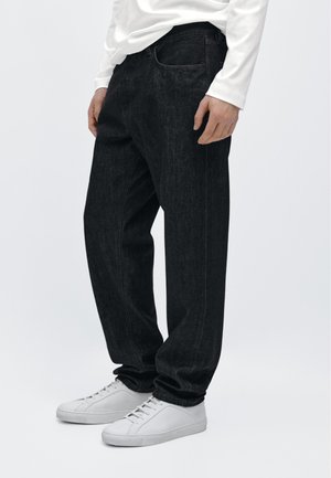 Czarne dżinsy z denimu o luźnym kroju, z klasycznymi detalami kieszeni i gładką fakturą, zestawione z białymi trampkami.