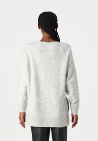 Pull oversized gris clair avec manches longues, col rond, poignets et ourlet côtelés, et en matériau doux et texturé.