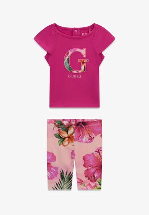 Haut rose vif à manches courtes avec un logo floral « G » et un short assorti imprimé floral avec des fleurs tropicales roses et vertes.