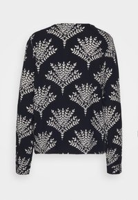 Blouse marine à manches longues vue de dos, avec un motif de feuilles blanches et un col arrondi. Tissu doux avec une coupe décontractée.