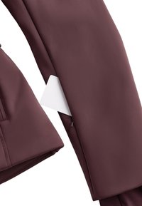 Bordo jakna glatke teksture s bočnim džepom. Bijela oznaka djelomično je vidljiva kroz patentni otvor na rukavu.