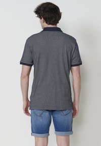 Námořnická polo košile s krátkým rukávem a límečkem, doplněná o ohrnuté džínové šortky. Košile má kontrastní lemování kolem rukávů.