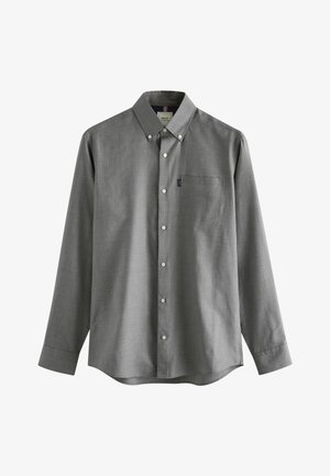 Cămașă gri cu mâneci lungi, din material texturat. Are o buzunar pe piept, o etichetă mică cu logo și nasturi albi.