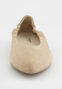 Beżowy balerinek zamszowy z marszczonym elastycznym tyłem i zaokrąglonym noskiem, widziany z przodu na białym tle.