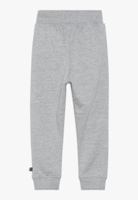 Szürke pamut jogger nadrág elasztikus derékkal, beszűkített lábakkal és bordázott mandzsettákkal. A side seam-en egy kis logó címke található.