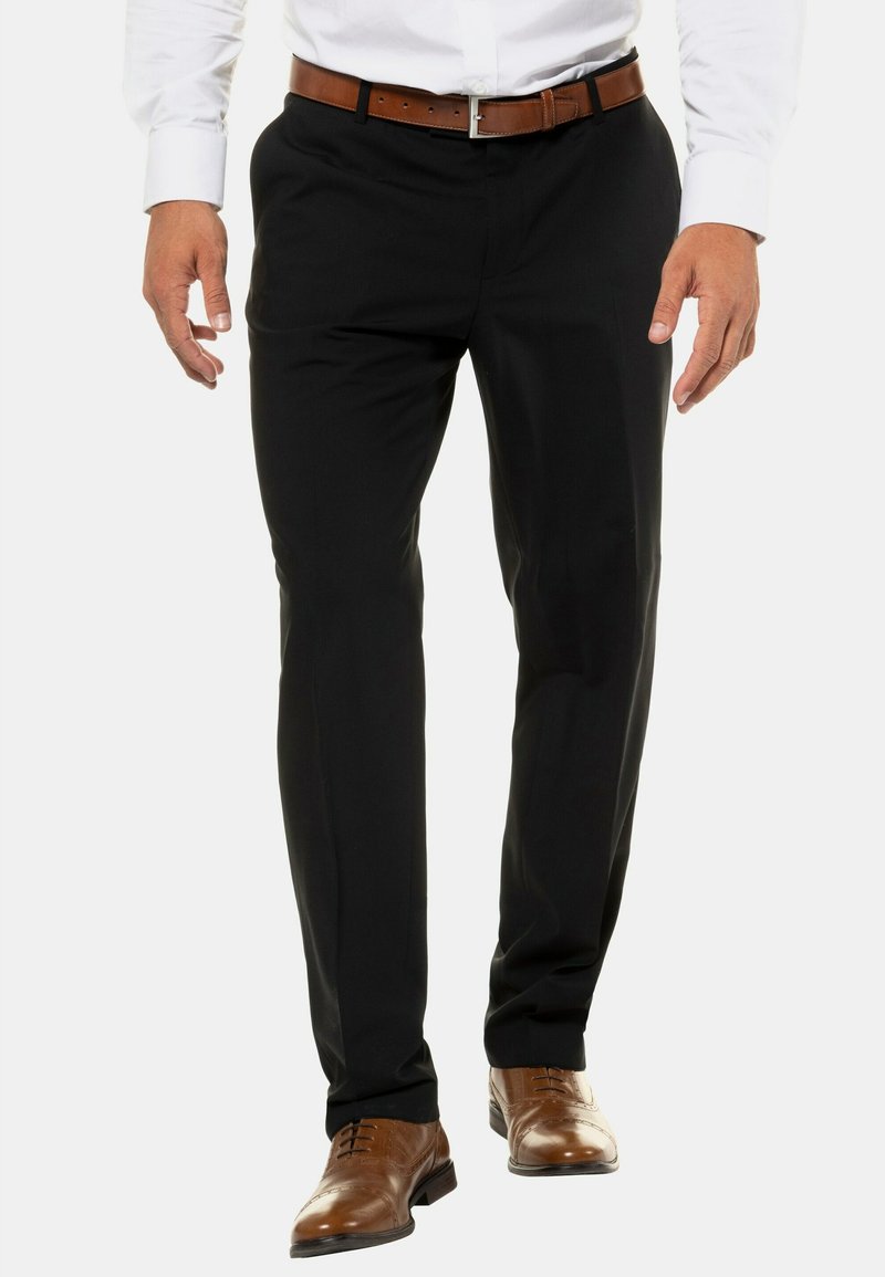Pantalones negros ajustados con una textura suave, combinados con una camisa blanca y un cinturón marrón. Acompañados de unos zapatos de vestir marrones.