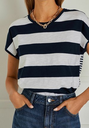 Camiseta a rayas en azul marino y blanco con un corte relajado, tejido suave, mangas cortas y escote redondo, combinada con jeans de cintura alta.